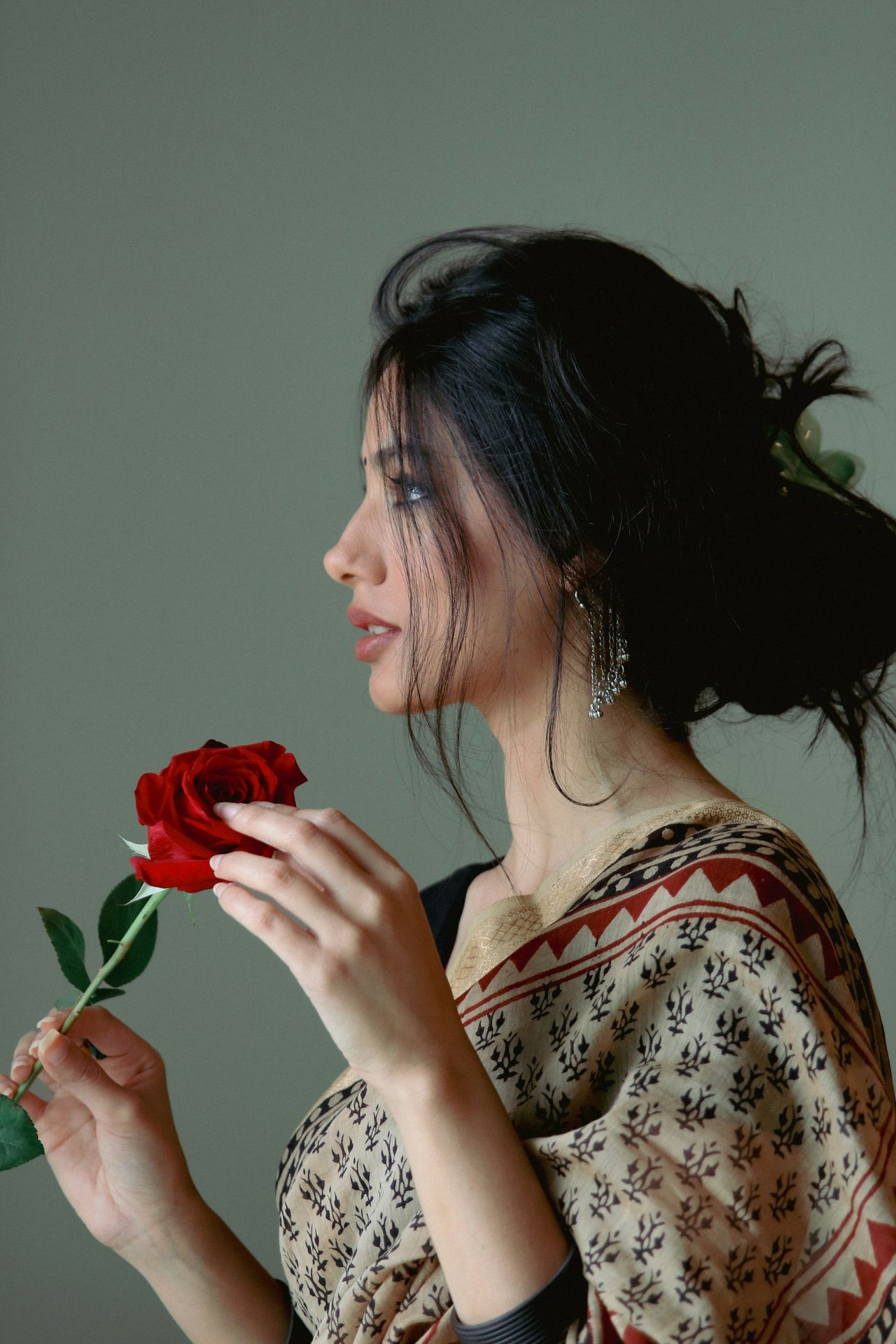 A woman is holding a rose in her hand